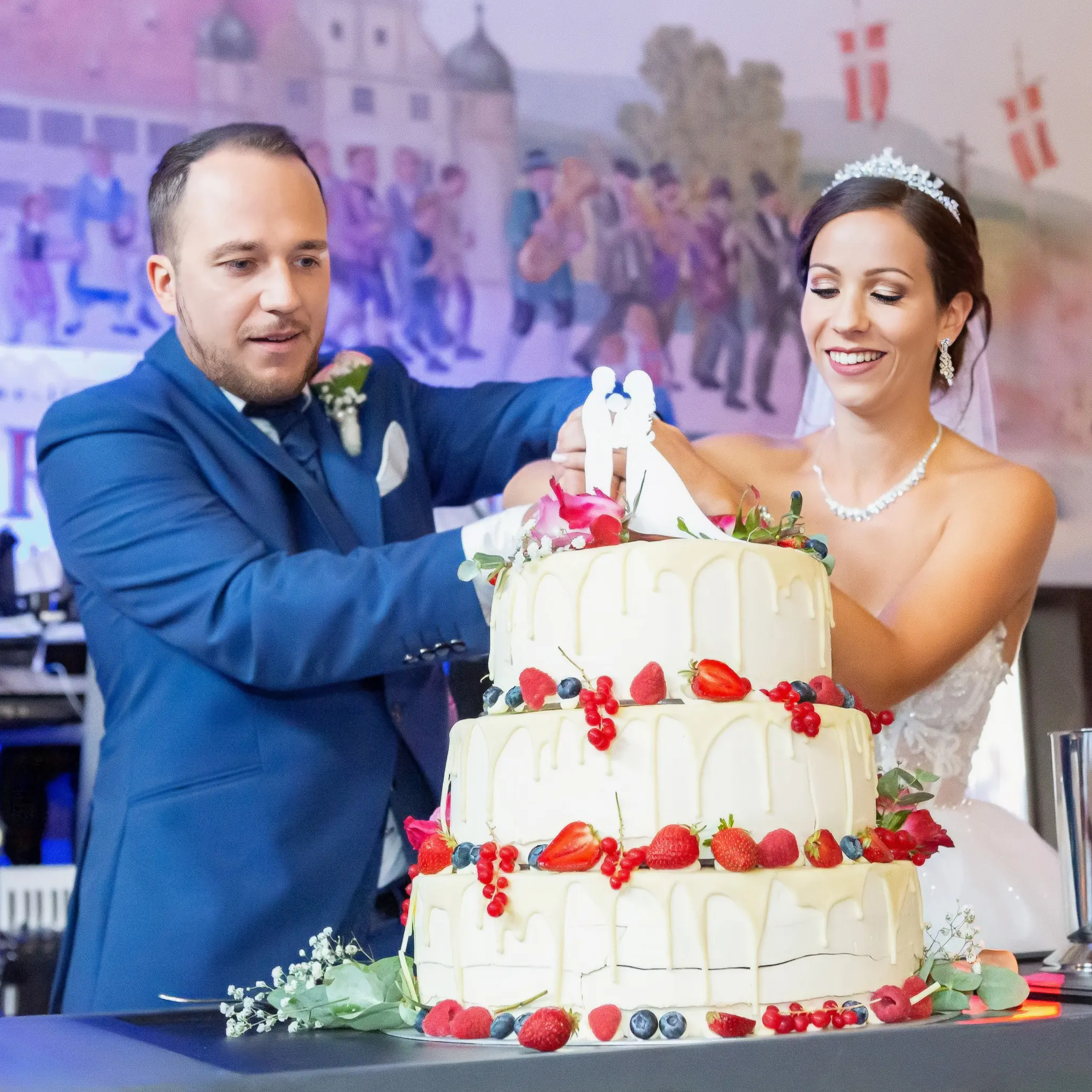 Dass Brautpaar schneidet gemeinsam ihre Hochzeitstorte an und sehen glücklich und feierlich aus